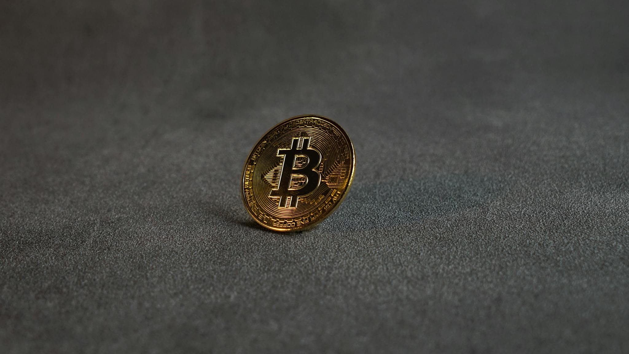 Close-up image of a golden Bitcoin standing on a grey surface, symbolizing cryptocurrency and digital finance.